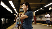July 2006, New York, N.Y. - A straphanger wipes the sweat from her face as she simmers in a stifling subway station shortly before the morning rush during a heat wave.