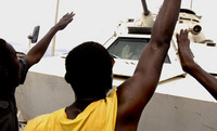 Haitian youth rush a UN tank during a rally for presidential candidate Rene Preval in Cite Soleil.