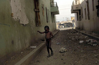 A young boy pulls his toy cart through the streets of La Saline.