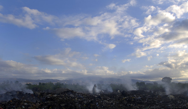 A lone woman wanders through vast fields of burning garbage searching for items to salvage on the outskirts of Port-au-Prince. : Haiti 2006 : Jason DeCrow Photojournalist