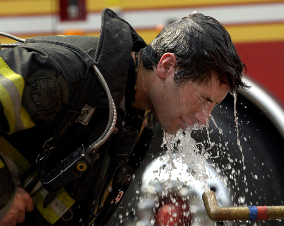 July 2005, Richmond Hill, N.Y. - A firefighter tries to escape the blistering summer heat by dousing himself after battling a two-alarm fire in Richmond Hill. : News Singles : Jason DeCrow Photojournalist