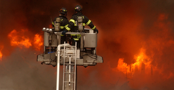 January 2005, Long Island City, N.Y. - Firefighters atop a tower ladder stare down into the fiery maw of a four-alarm blaze at a chemical warehouse in Long Island City. : News Singles : Jason DeCrow Photojournalist