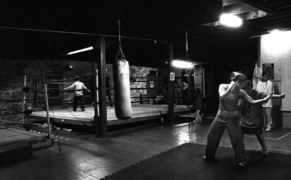 Surrounded by bare brick walls, rickety wooden floors and two tattered boxing rings, Kate Reulbach, 21, helps Israel Rolon, 13, with his jab. : Fighting the Streets : Jason DeCrow Photojournalist