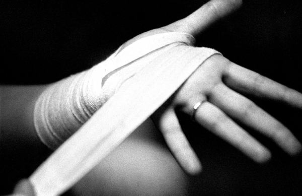 Wrapping the hands is a delicate operation for fighters.  Too loose and the lack of support can mean broken bones, too tight and the wraps will cut off circulation to the hands.  Kate works  to get her wraps just right. : Fighting the Streets : Jason DeCrow Photojournalist