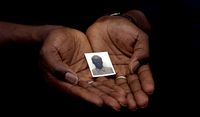 August 2005, New York, N.Y. - A photograph of slain Senegalese livery driver Modou Diop is cradled in the hands of his friend and coworker a day after he was shot to death while working in the Bronx.